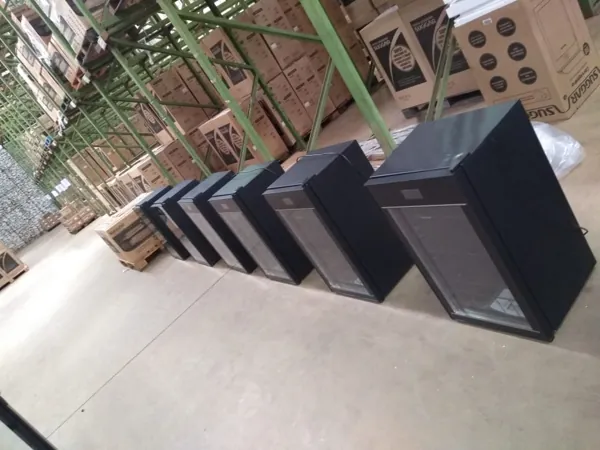 Geladeiras envelopadas em preto alinhadas em galpão