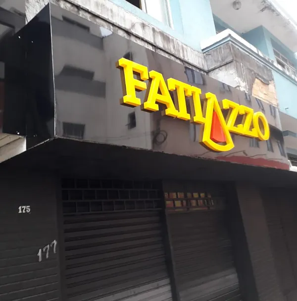 Letreiro amarelo Fatiazzo em fachada escura